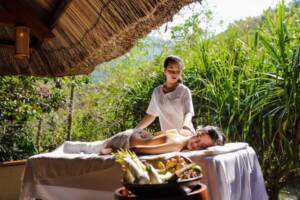 Donna che riceve un massaggio rilassante alla schiena in una spa all'aperto circondata dalla natura tropicale durante un viaggio organizzato vietnam 10 giorni.