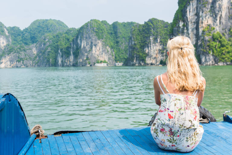 The woman sitting on the deck of the ship looking view of Halong Bay